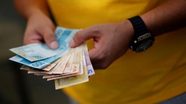 homem segurando notas de real