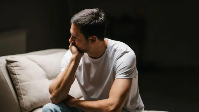 Um homem sentado em um divã perdido em seus pensamentos