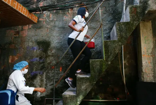 Duas mulheres sobem escada em área externa de casa