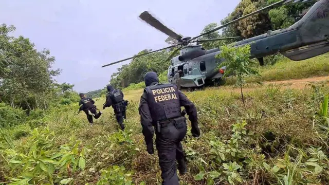 Foto mostra agentes da PF se aproximando de um helicóptero em uma área de floresta na Terra Indígena Yanomami, em Roraima